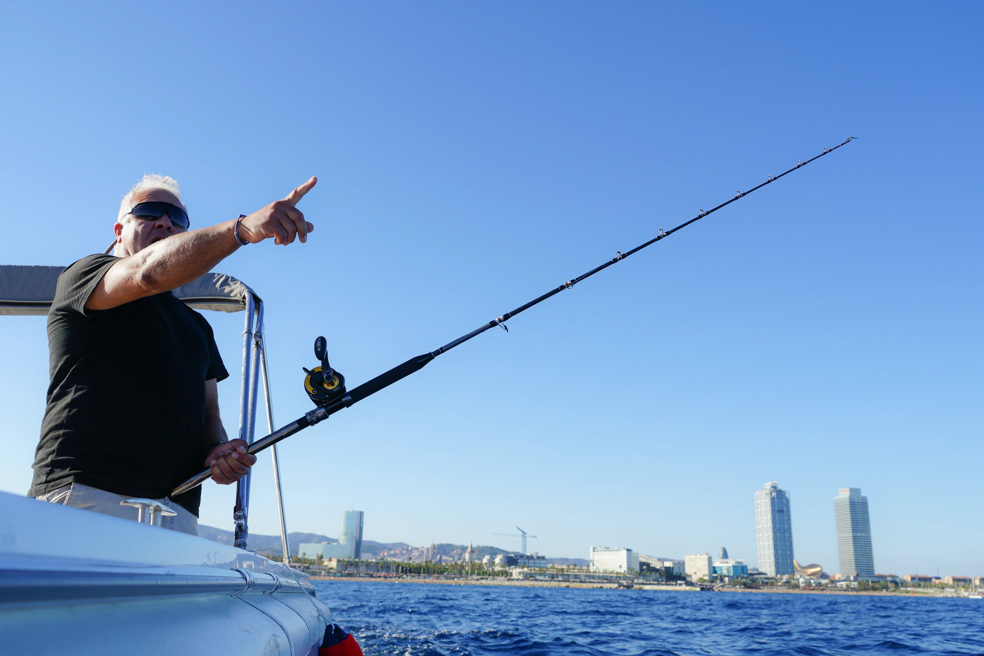 Man holding a fishing rod and pointing at the horizon