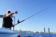 Muž drží rybářský prut a ukazuje k obzoru