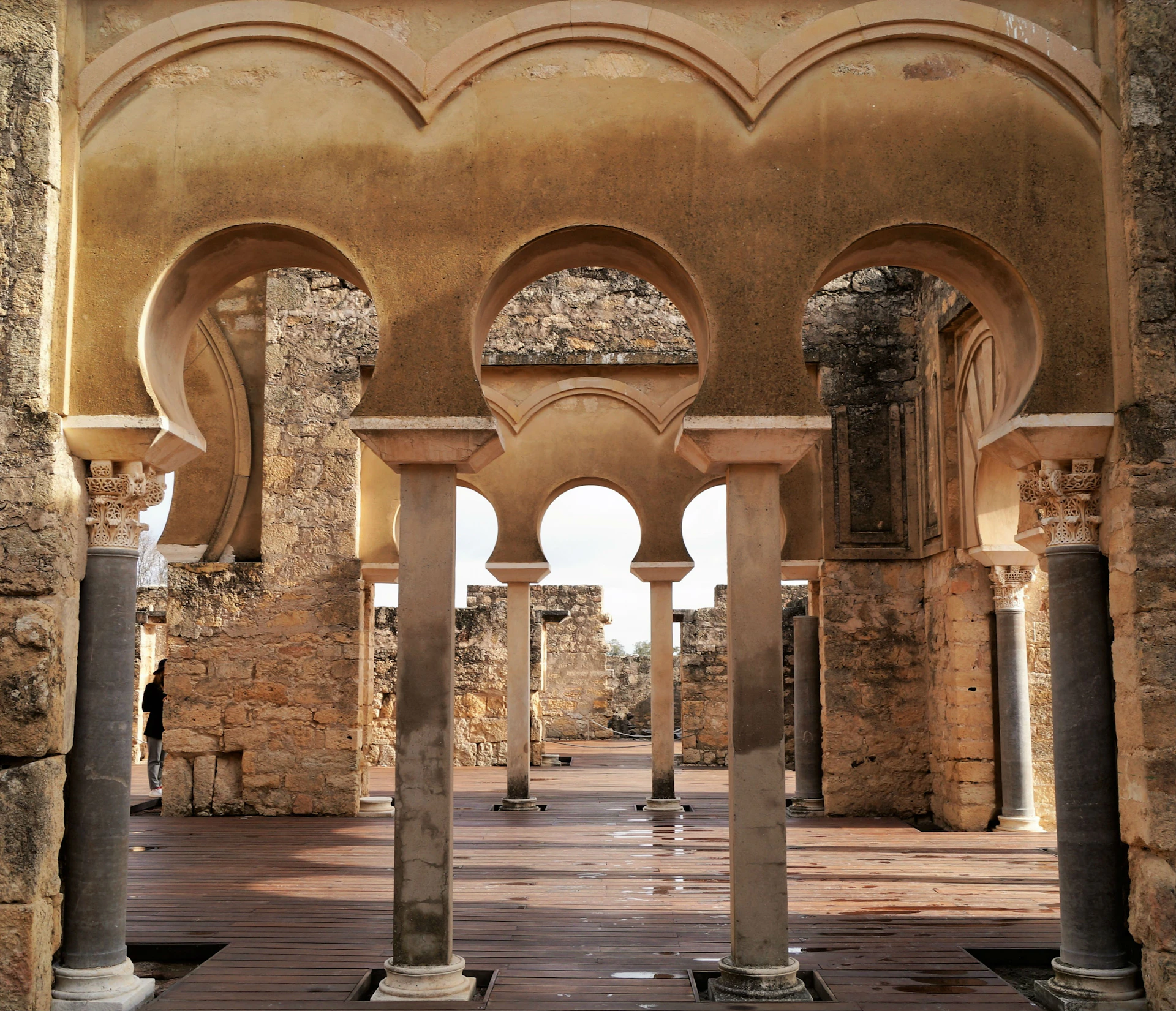 Stone arches and columns in a historical ruin, with intricate detailing and a partially open roof.
