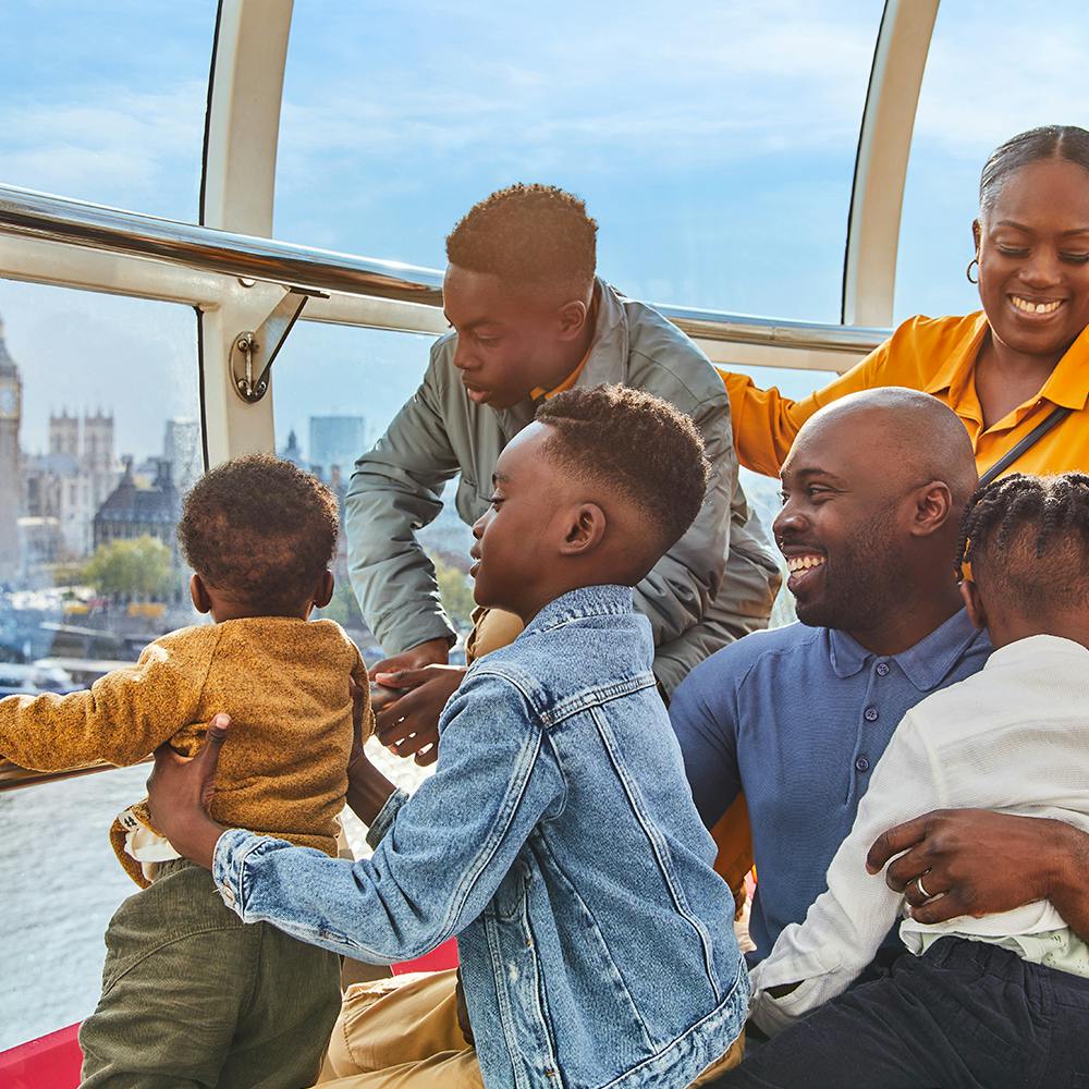 Šťastná rodina s malými dětmi má z prosklené vyhlídkové kajuty výhled na panorama města.