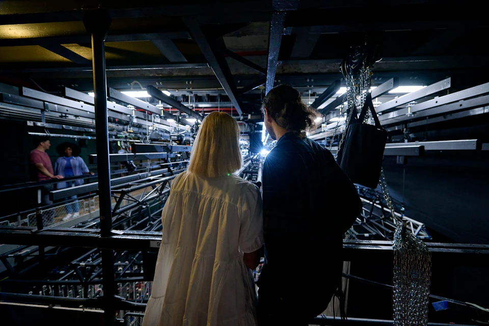Guests overlooking the lighting railing where theatre crew set up stage lights