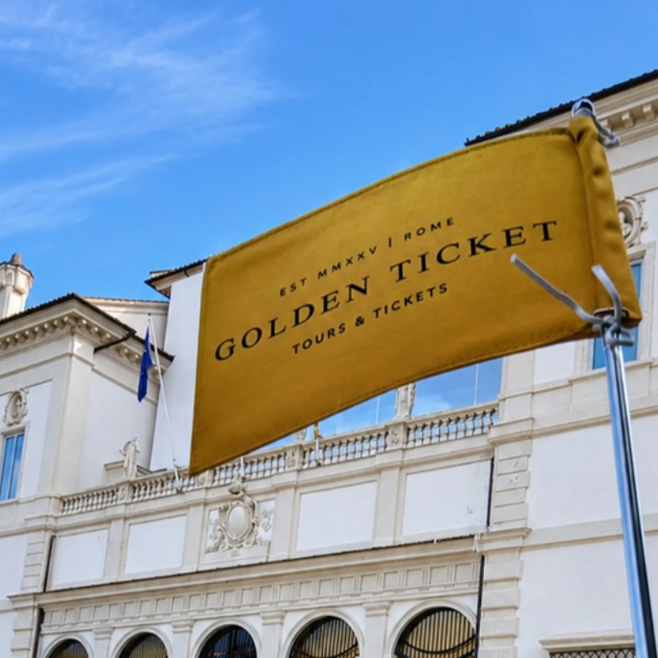 A yellow flag reading 'Golden Ticket Tours & Tickets' in front of a white classical building under a blue sky.