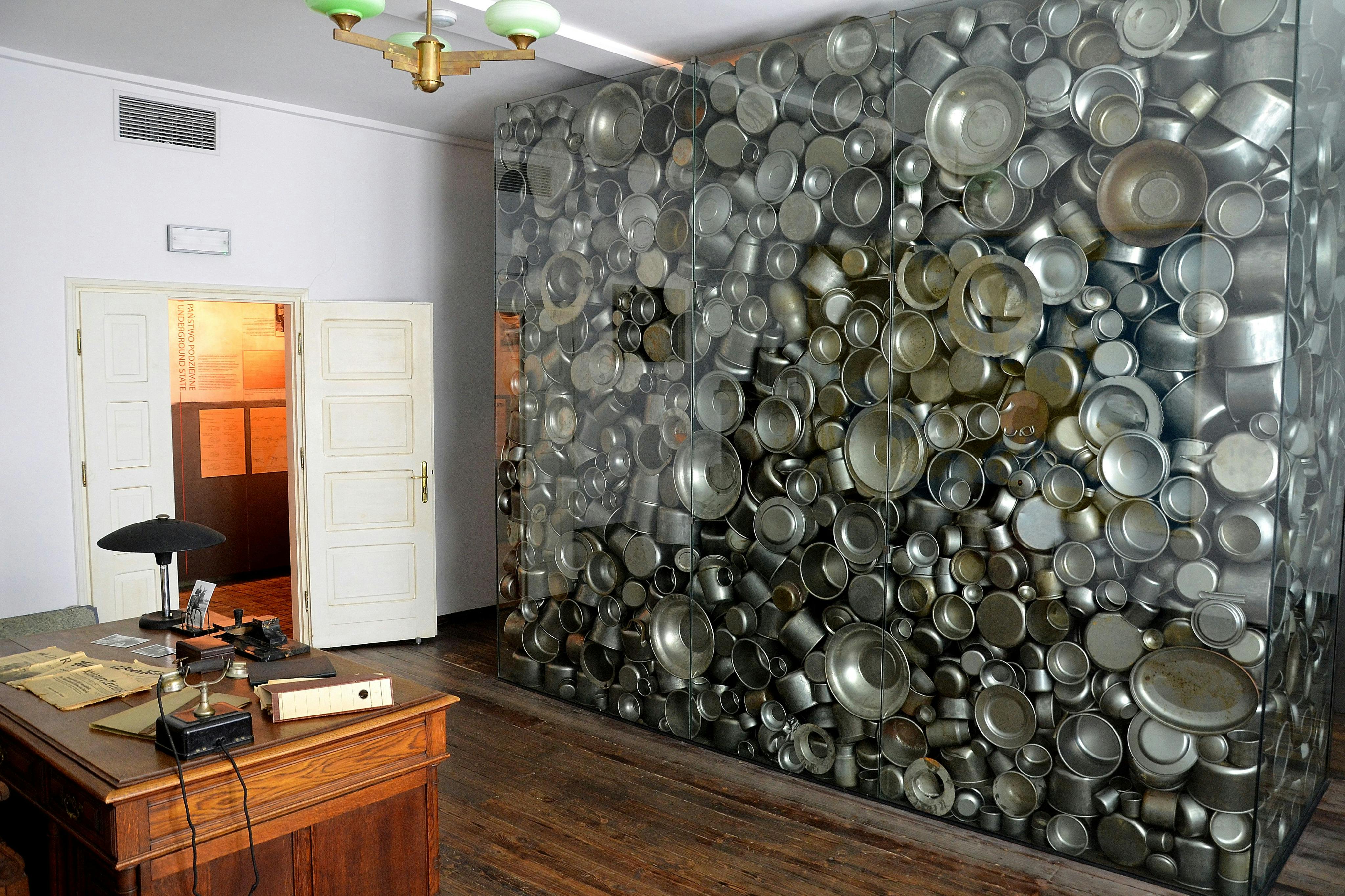 房间门开着，墙上挂满了金属锅和平底锅，桌子是木制的，天花板是绿色的。