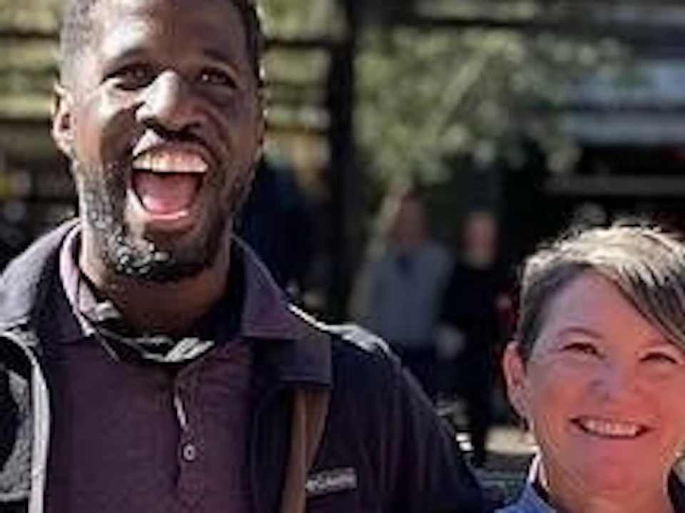 A group of six people standing outside Ponce City Market on a sunny day, holding drinks and smiling towards the camera.