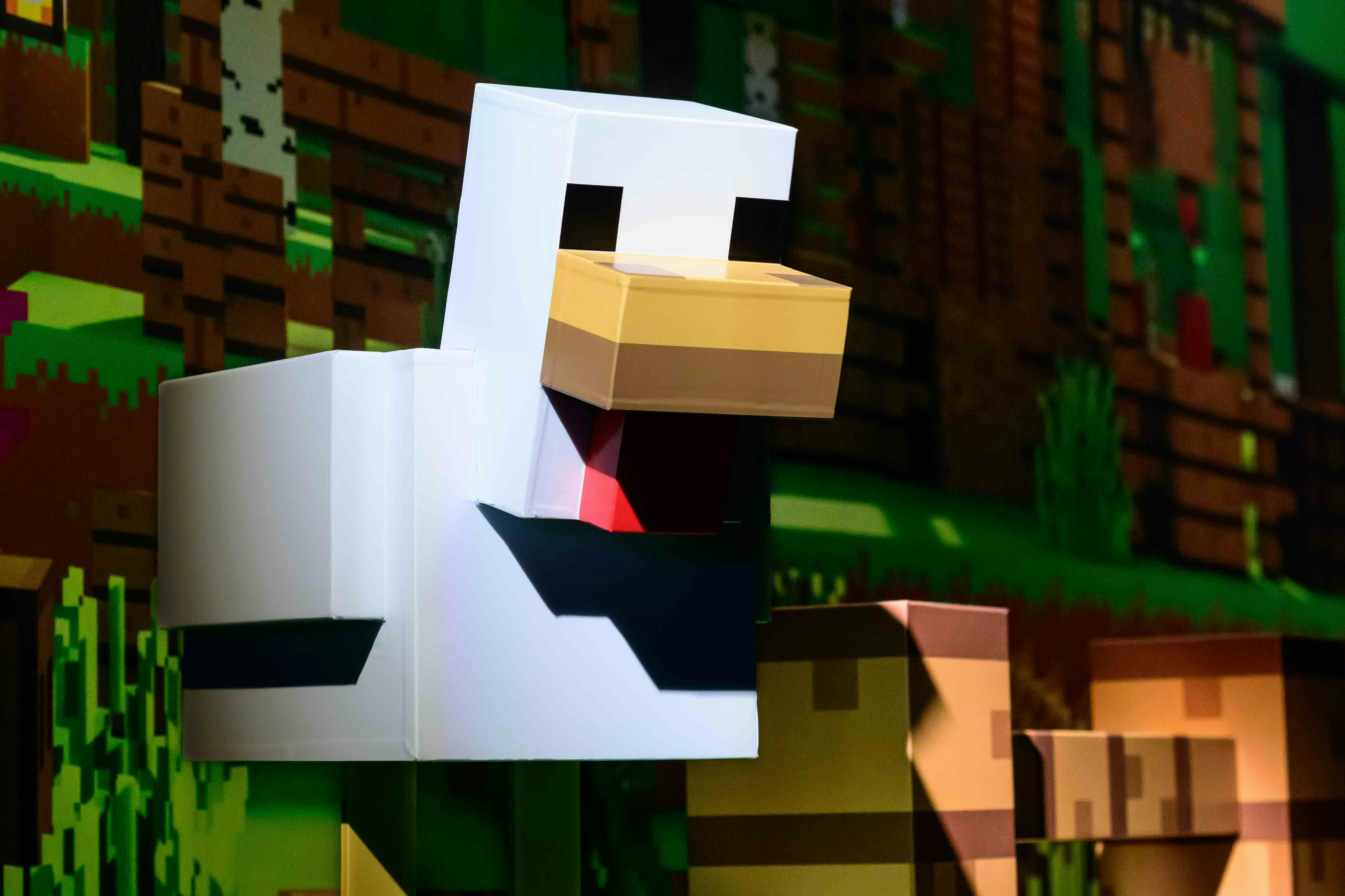 Пикселизированный, похожий на утку персонаж из Minecraft стоит в травянистой, лесистой среде.