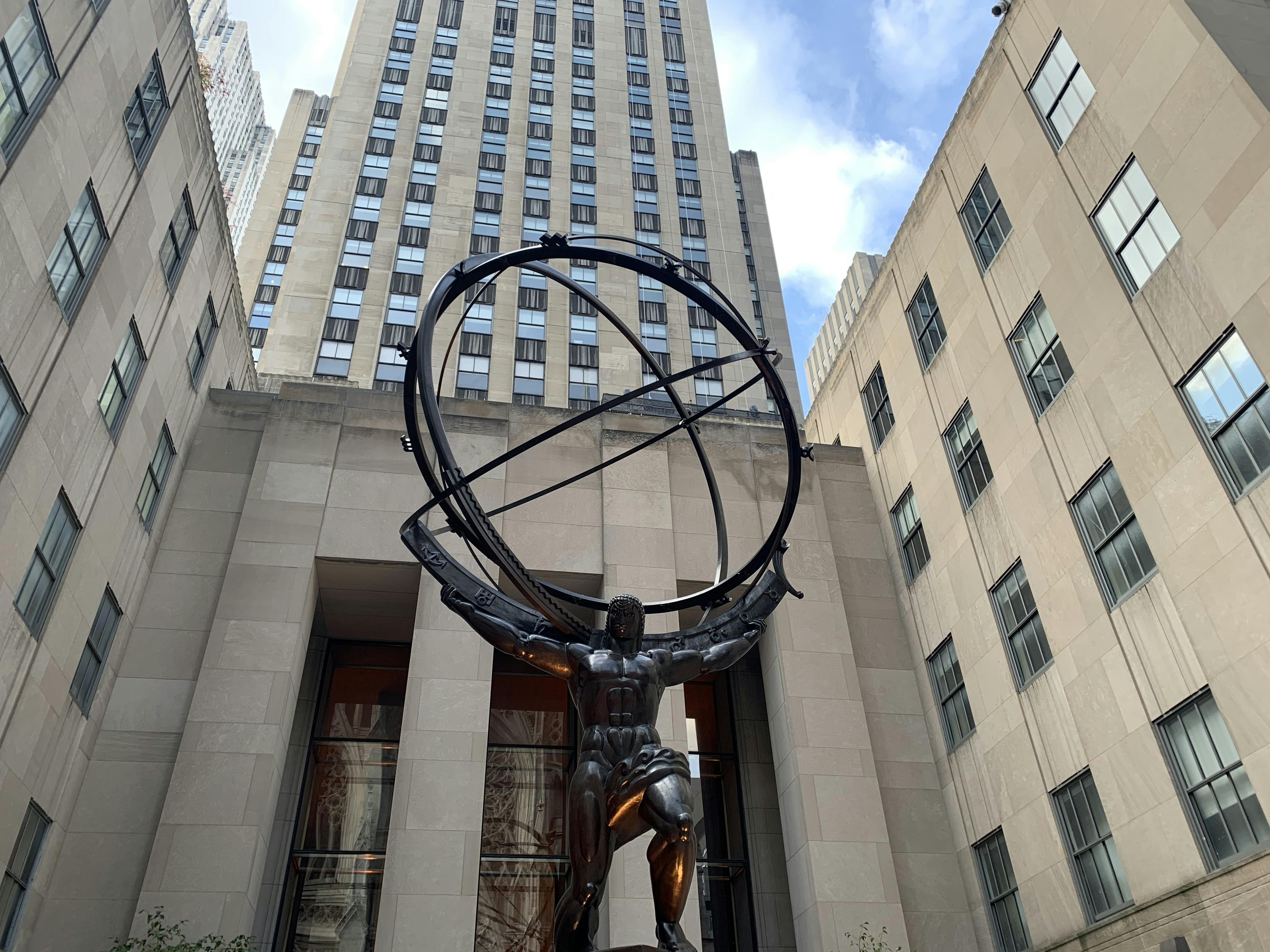 Χάλκινο άγαλμα του Άτλαντα που κρατά μια μεγάλη σφαίρα armillary, με ψηλά κτίρια γραφείων και ένα μερικώς νεφελώδη ουρανό στο παρασκήνιο.