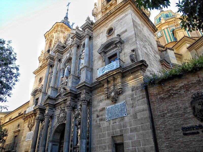 틈새, 높은 기둥, 디테일한 조각이 있는 화려한 석조 건물. 배경에는 돔의 일부가 보입니다.