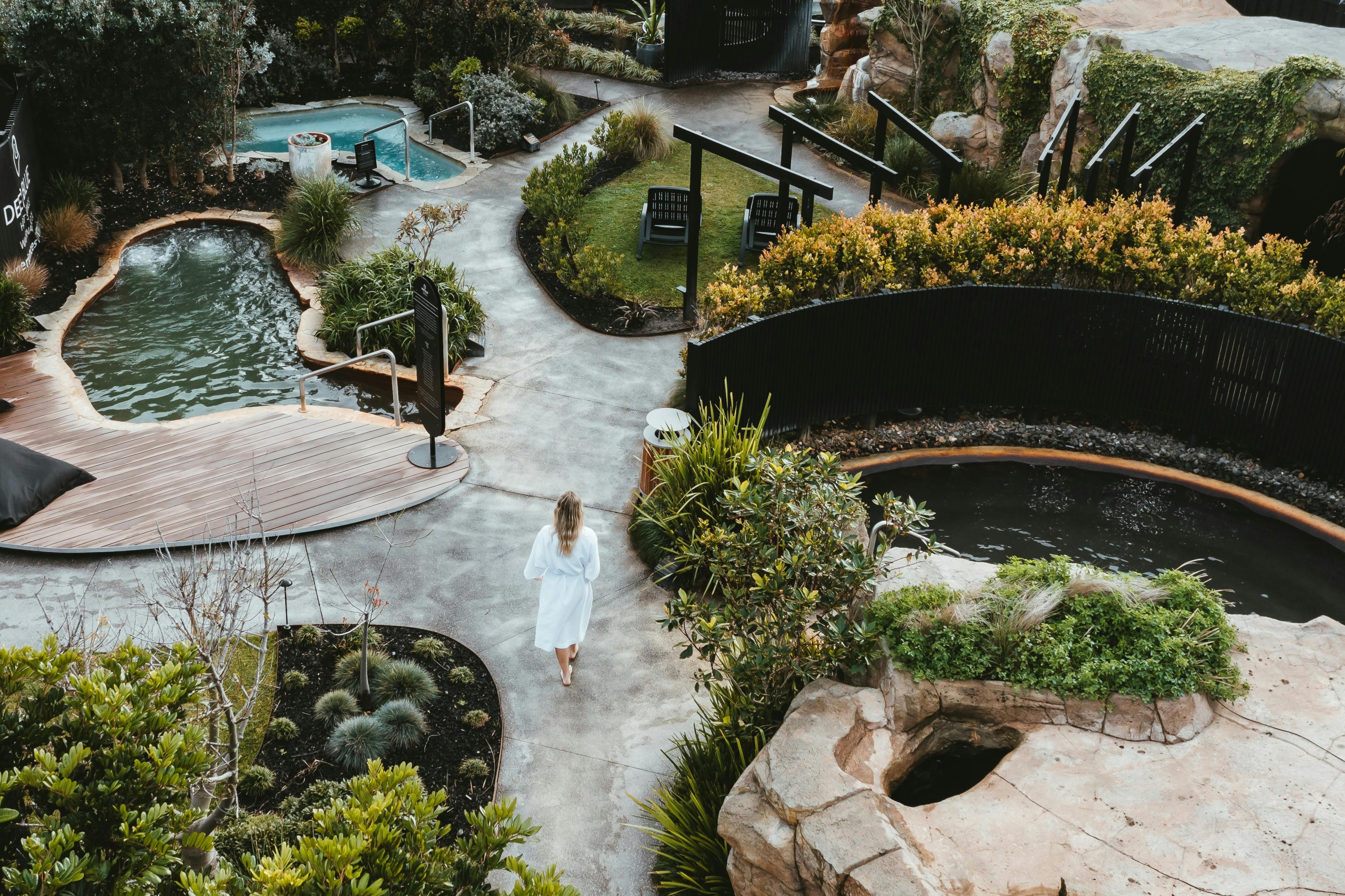 Veduta aerea di una donna che si aggira nel santuario con numerosi sentieri, vasche geotermiche, grotte e piscina fredda.