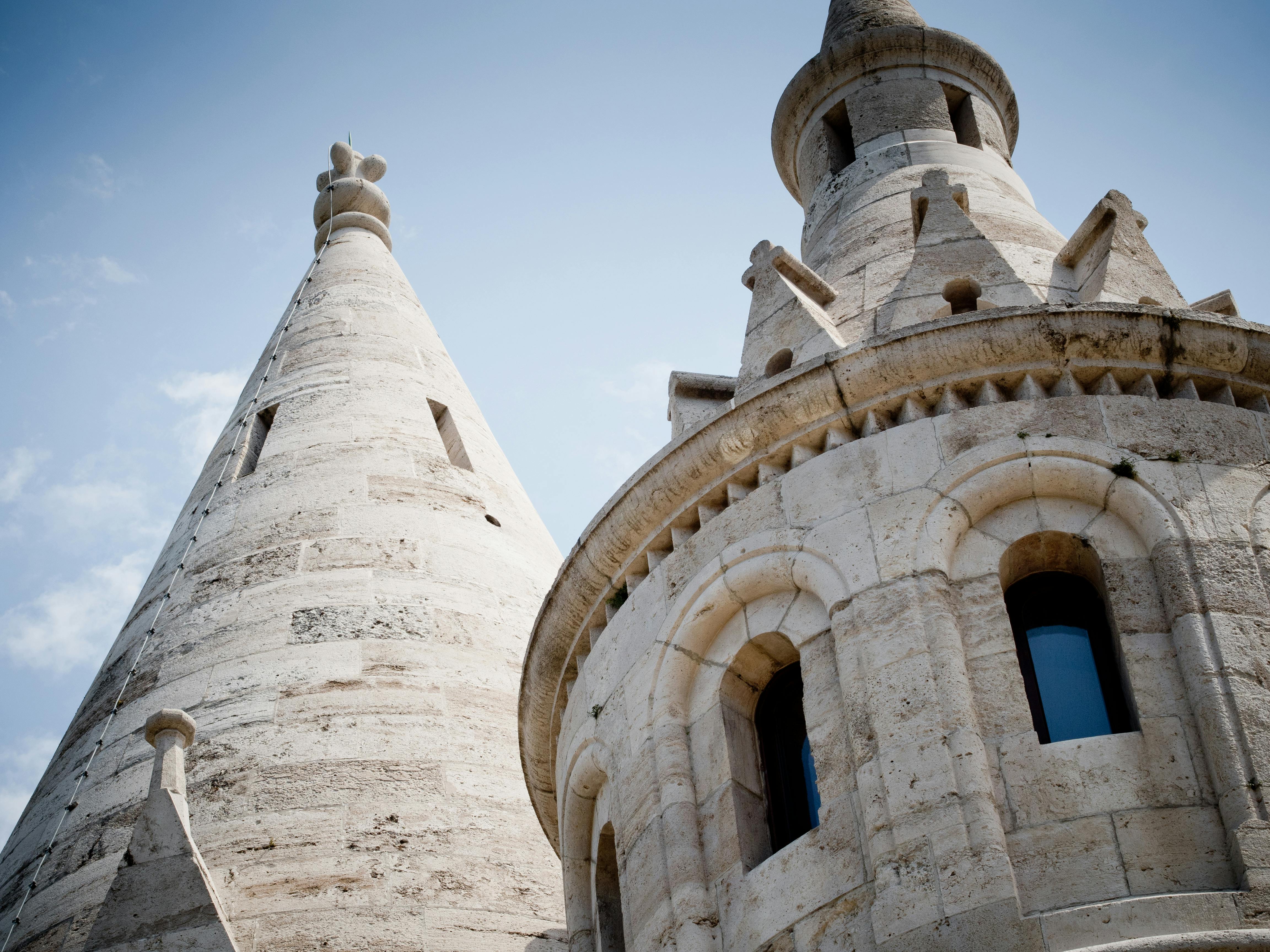 円錐形の屋根とアーチ型の窓を備えた2つの石造りの塔は、澄んだ青い空に面しています。