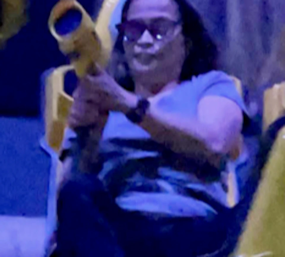 Four people wearing 3D glasses sit in yellow seats, aiming orange guns, with amusement park ride backgrounds visible.