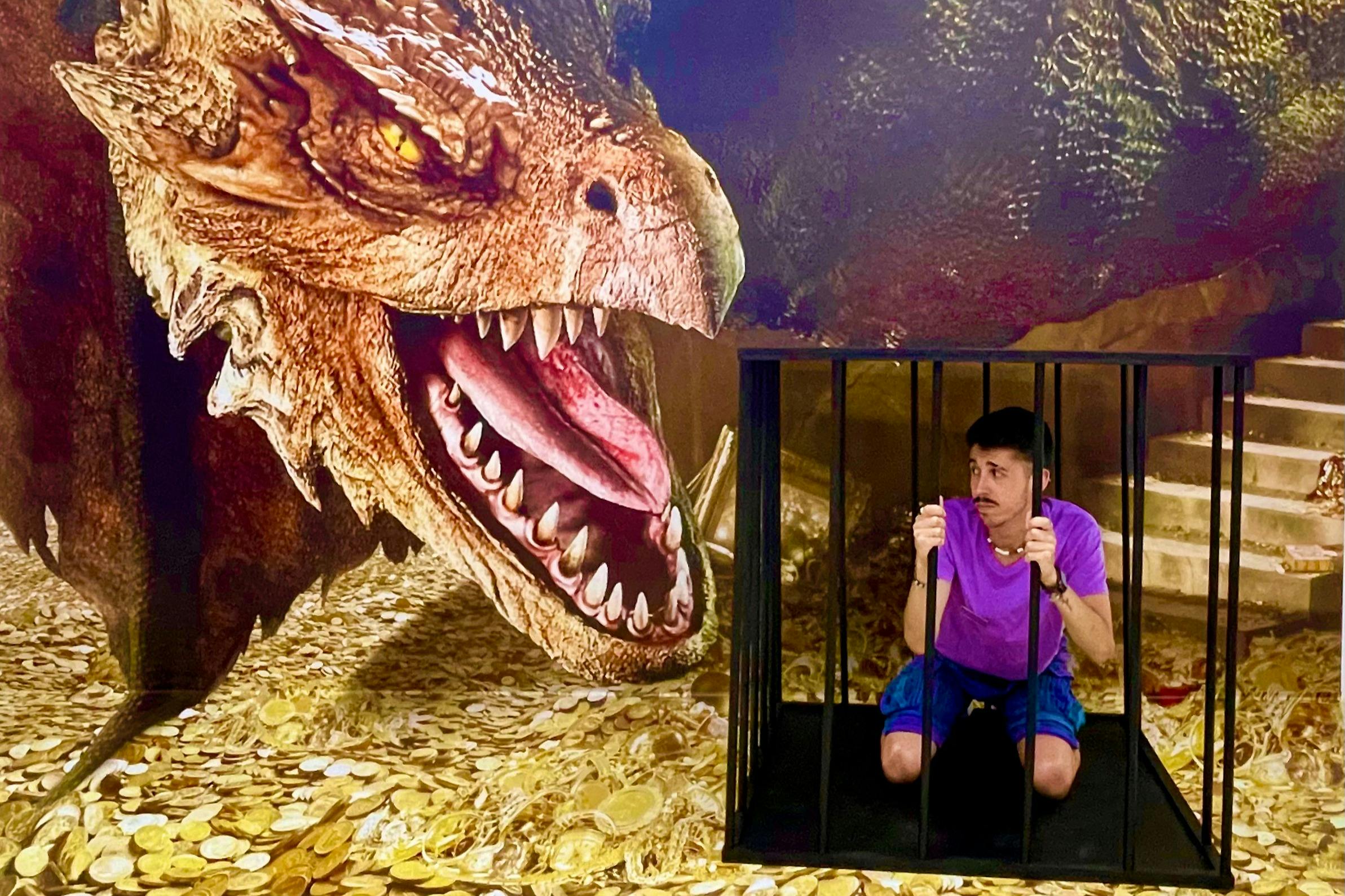Un home agenollat en una gàbia petita, amb un fons que representa un dinosaure i monedes d'or.