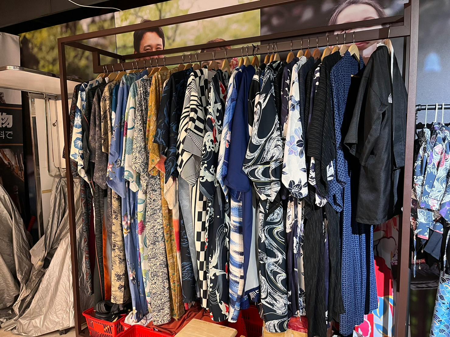 A rack of colorful kimonos and yukatas hanging on hangers in a shop, with various patterns and designs visible.