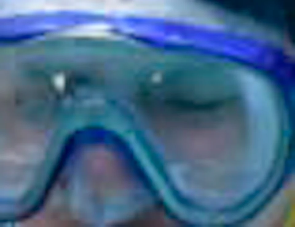Two people in a pool wearing snorkel gear, with beach balls floating nearby. One wears a swim cap, and both seem engaged in conversation.