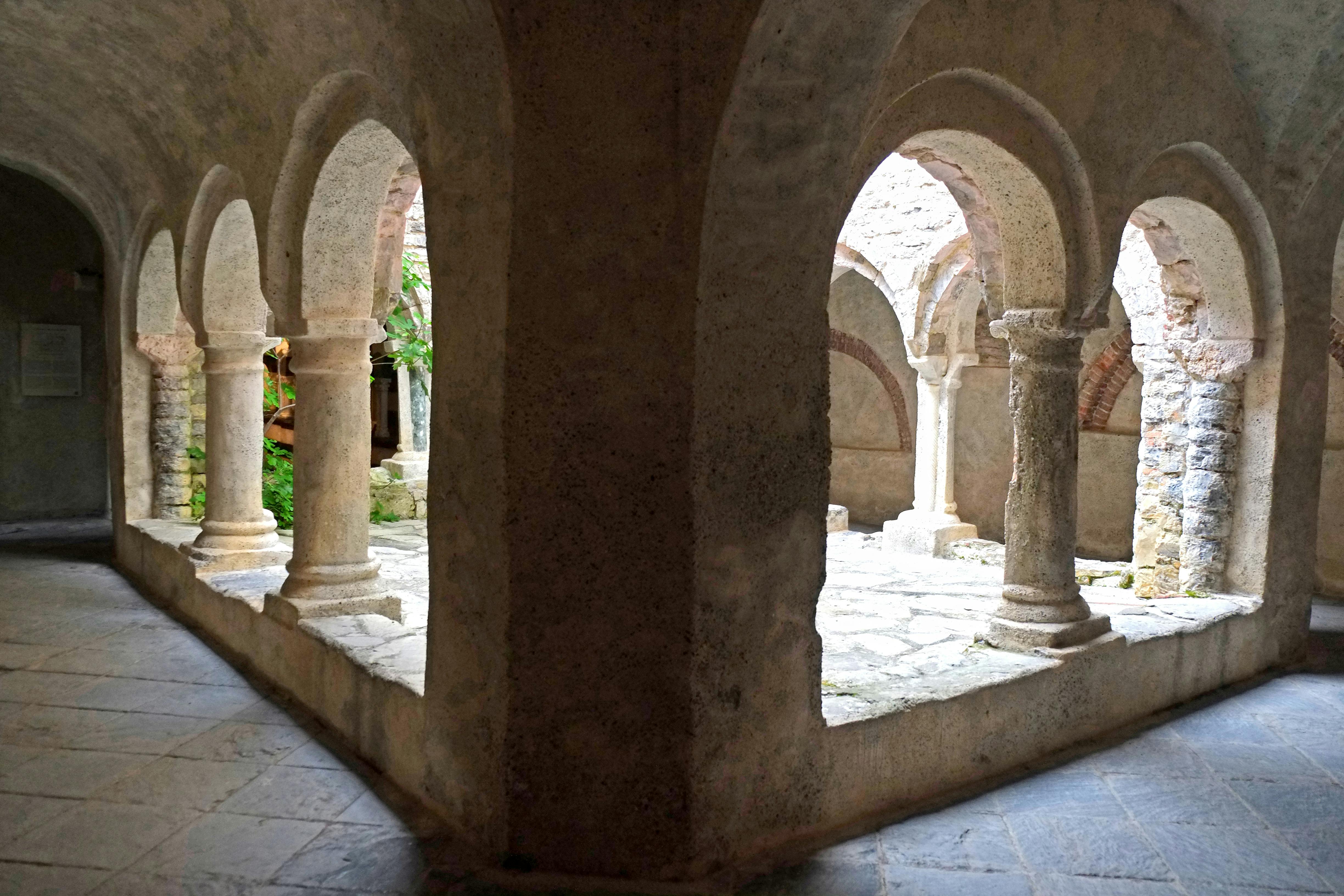 石拱门和石柱构成了一个局部庭院，鹅卵石地板，背景绿意盎然。