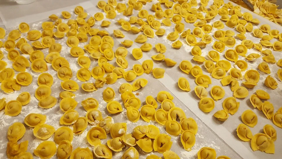 Dozens of freshly made tortellini spread out on floured parchment paper.