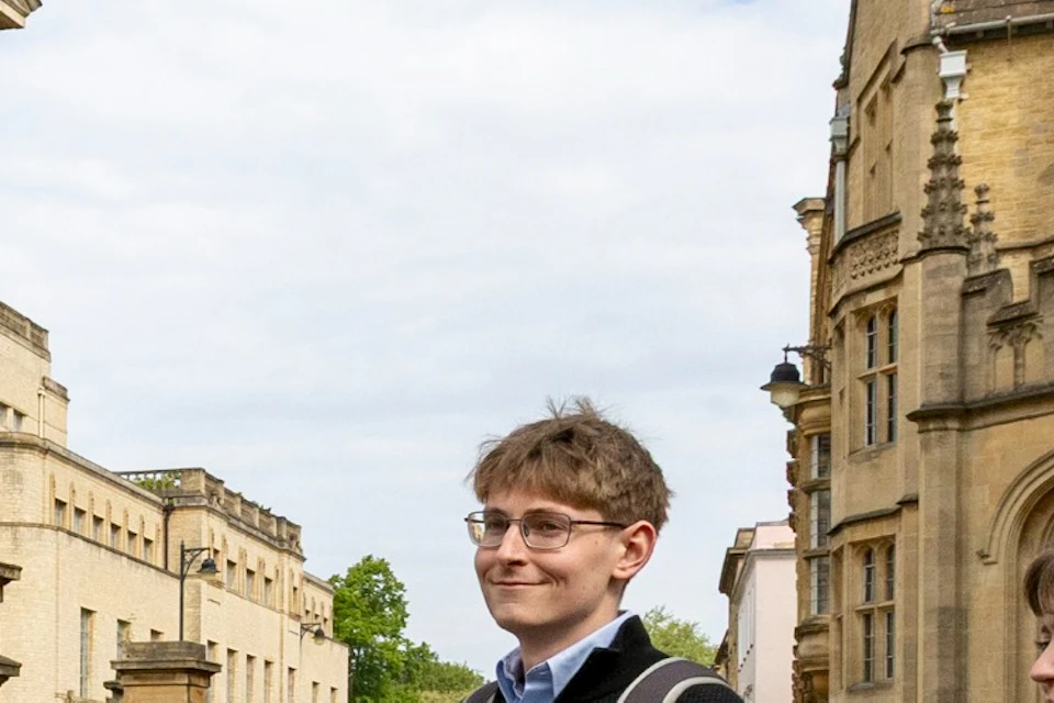 A group of people standing in an urban street near historic buildings, with one person speaking to the group.