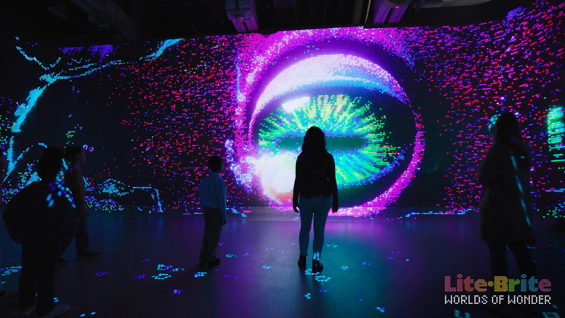 未来的なデザインの大きなカラフルなデジタルディスプレイの前に立つ大人と子供のシルエットフィギュア。