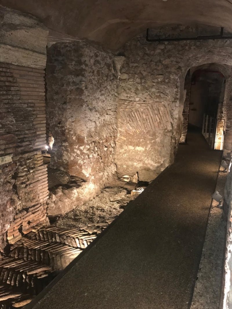 古老的地下走廊，石墙和砖拱门，灯光昏暗，通往拱形通道。