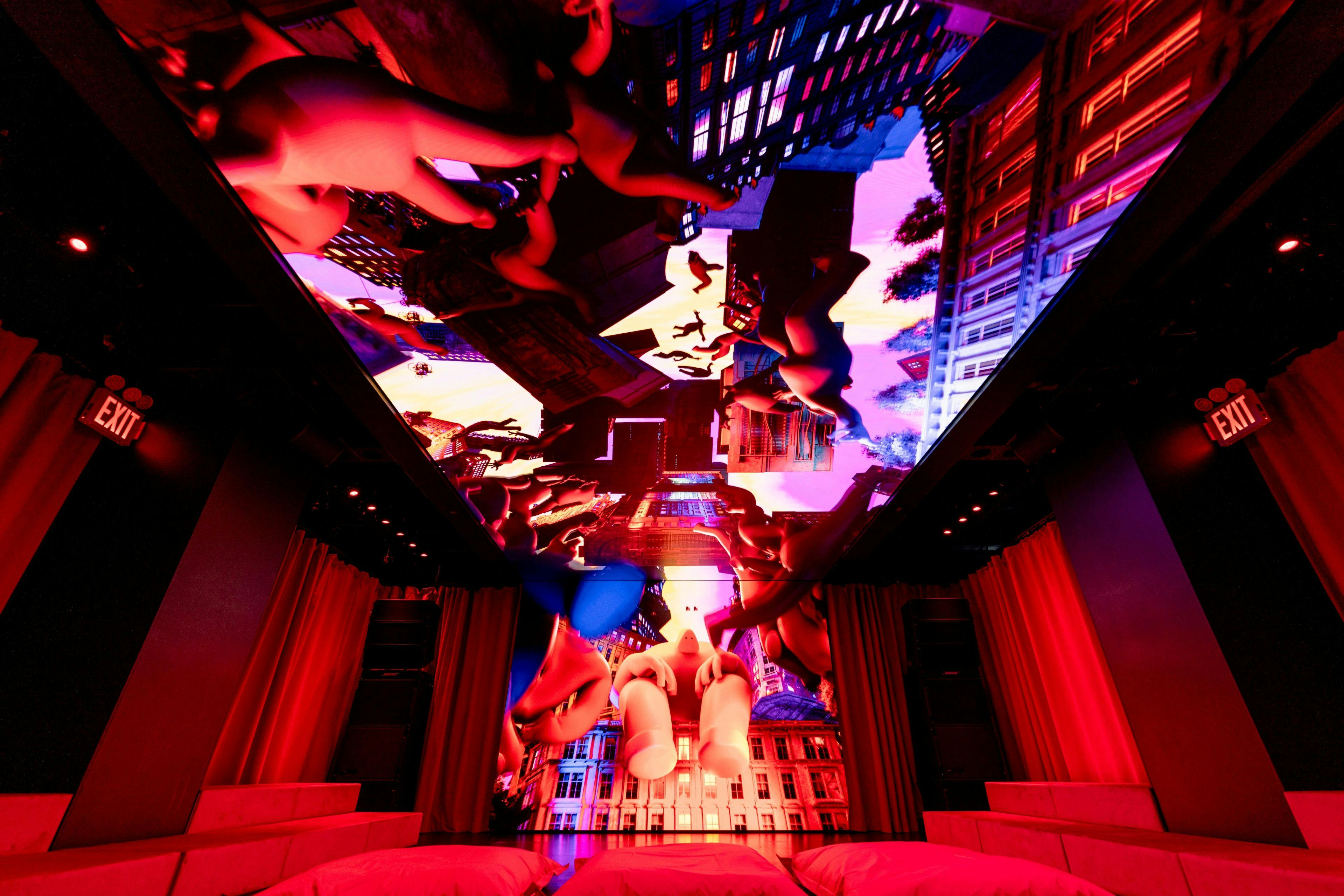 A vibrant ceiling display features colorful, abstract figures and cityscape elements with red lighting in a dark room setting.