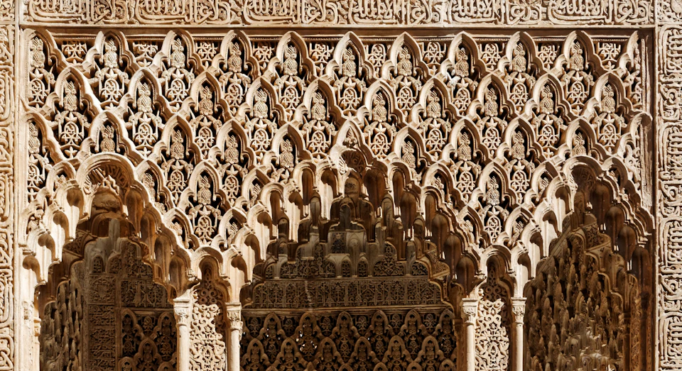 Intricately carved architectural wall with geometric and floral patterns, featuring a series of arches.