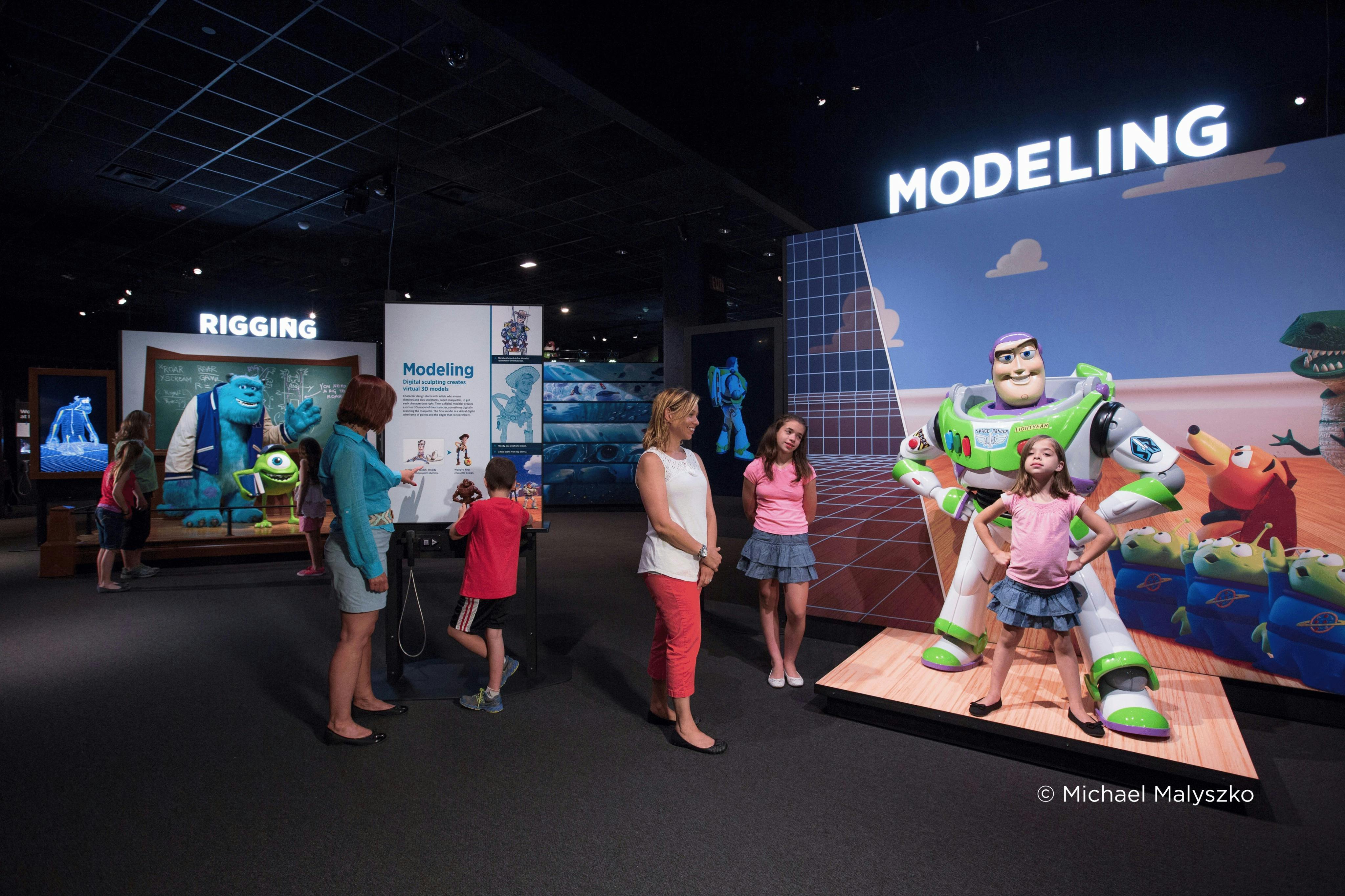 Visitantes en una exposición en la que se muestra una maqueta de Buzz Lightyear y se explican los procesos de modelado de animación.