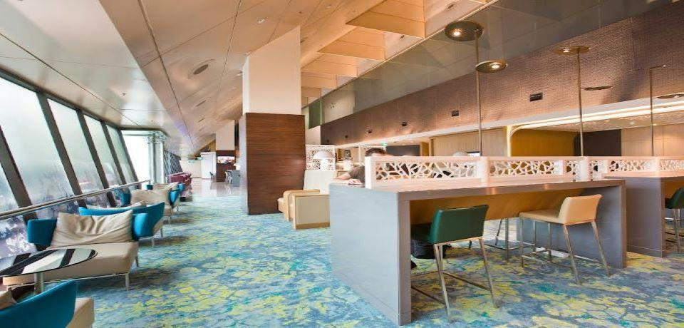 A modern lounge area with plush seating, colorful carpet, and partitions for privacy, featuring contemporary lighting.
