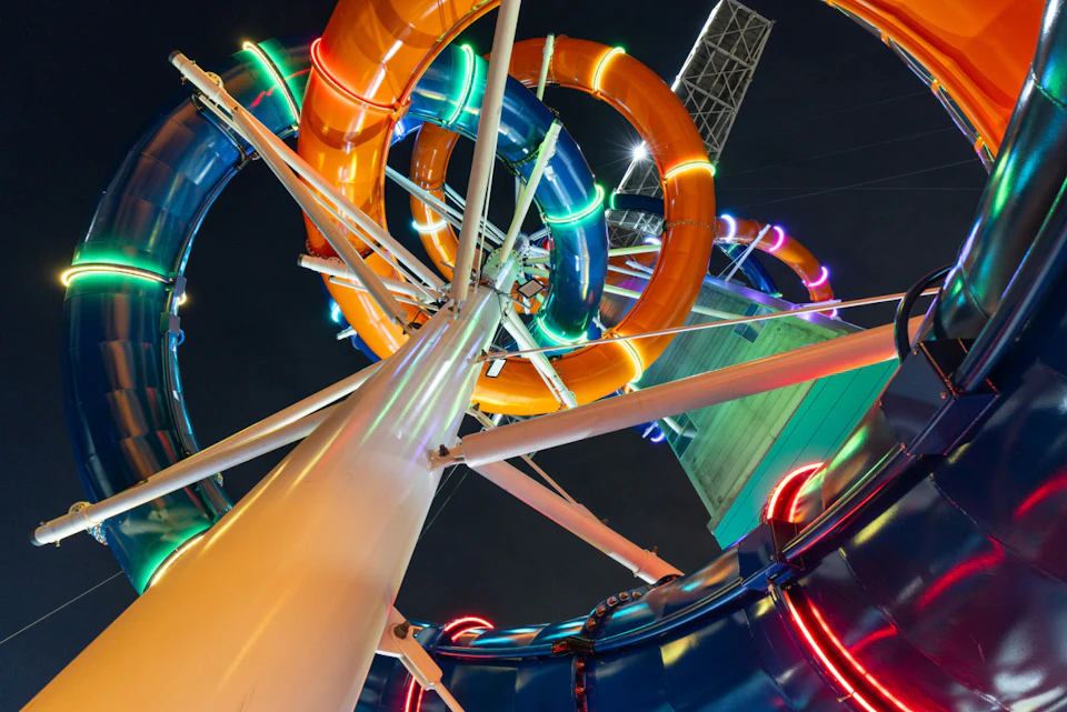 Colorful water slide tubes with neon lights viewed from below at night.