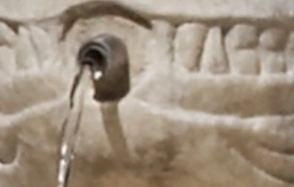 Ornate stone fountain supported by sculpted lions, with intricate arches and columns in the background.