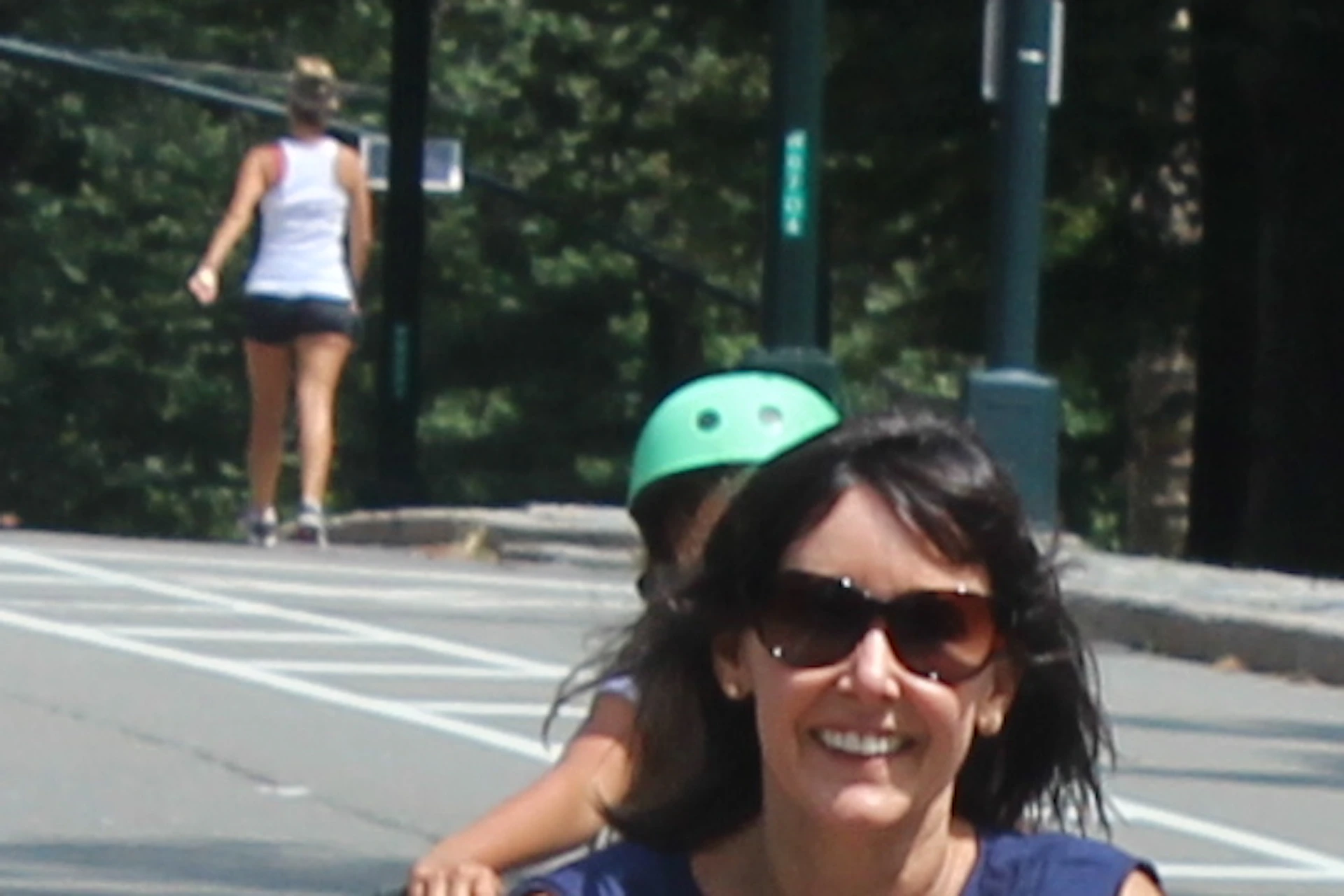 Five people riding bicycles on a tree-lined street, smiling and enjoying a sunny day.
