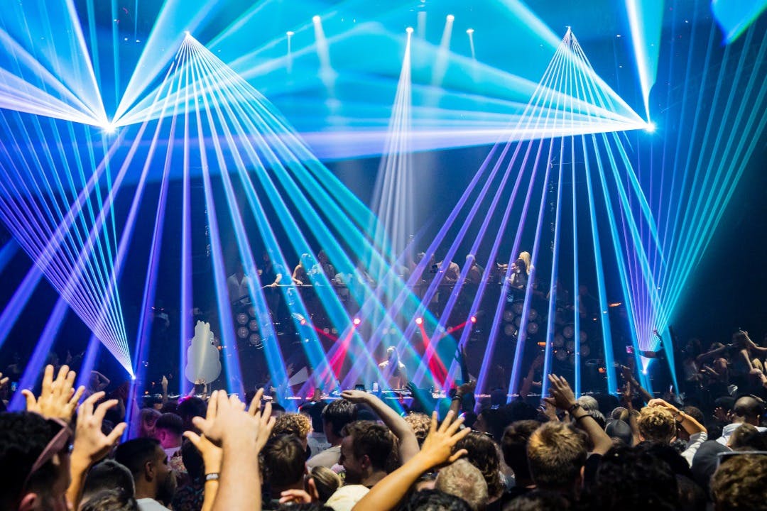 Dav, který si užívá koncert s živými modrými a fialovými laserovými světly osvětlujícími jeviště.