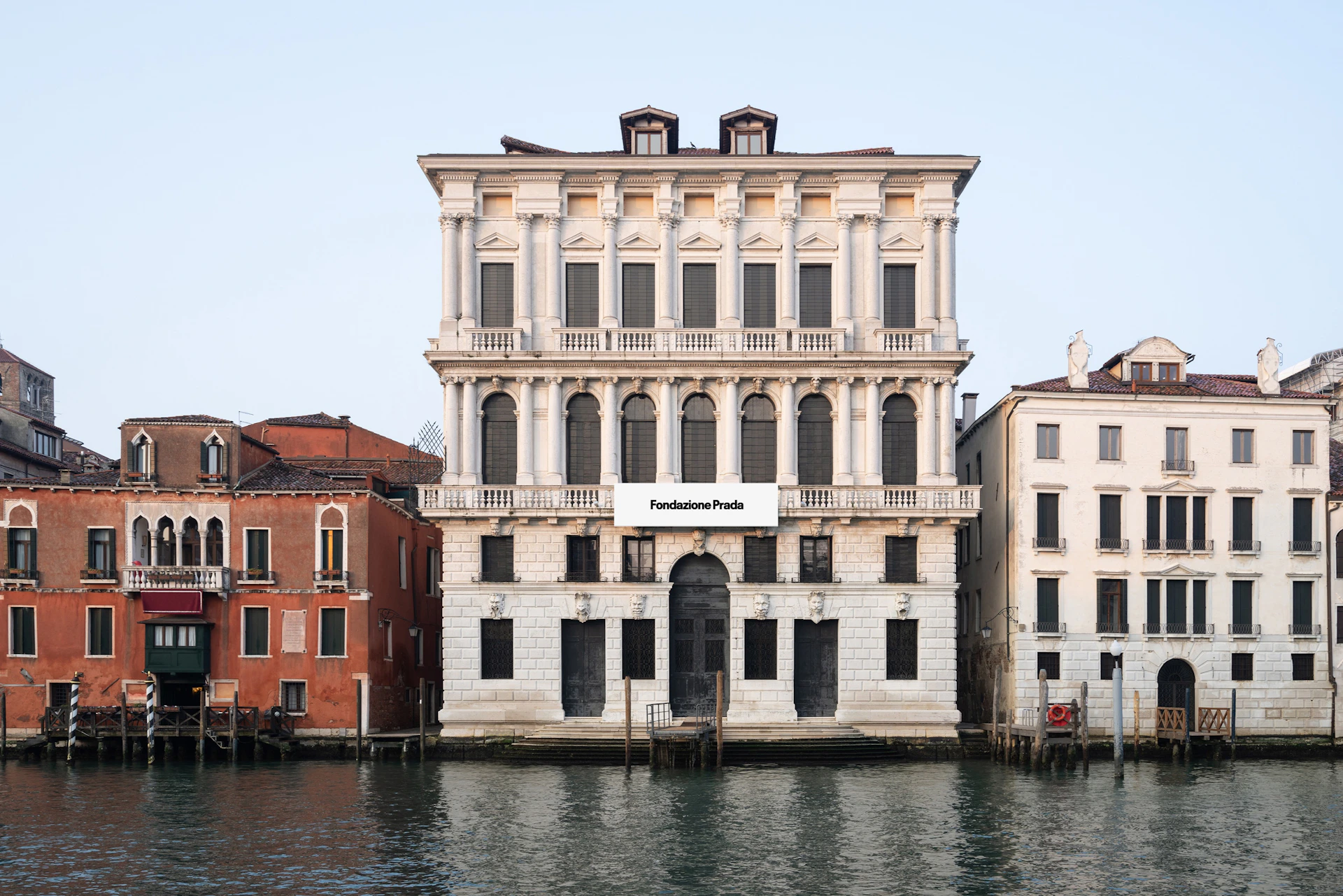 A classic-style building housing the Fondazione Prada, situated beside a canal amongst the neighbouring buildings in Venice.