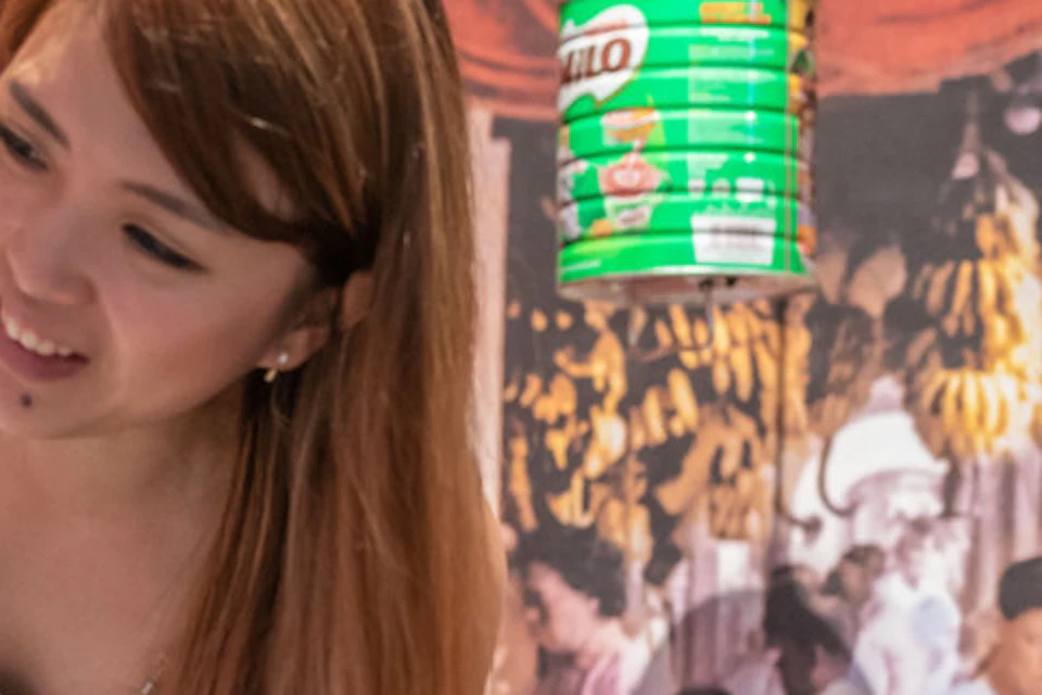 A woman and a child interact with a vintage vending machine in a colorful market-themed setting.