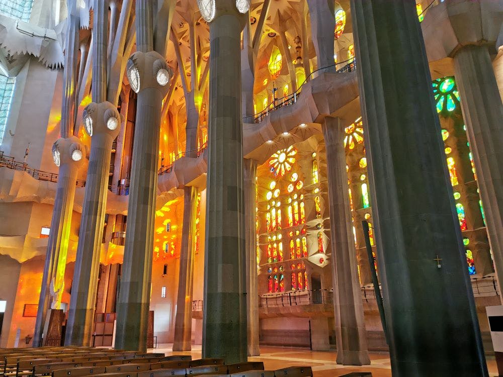 Interior of a cathedral with tall columns and colorful stained glass windows creating vibrant light patterns.