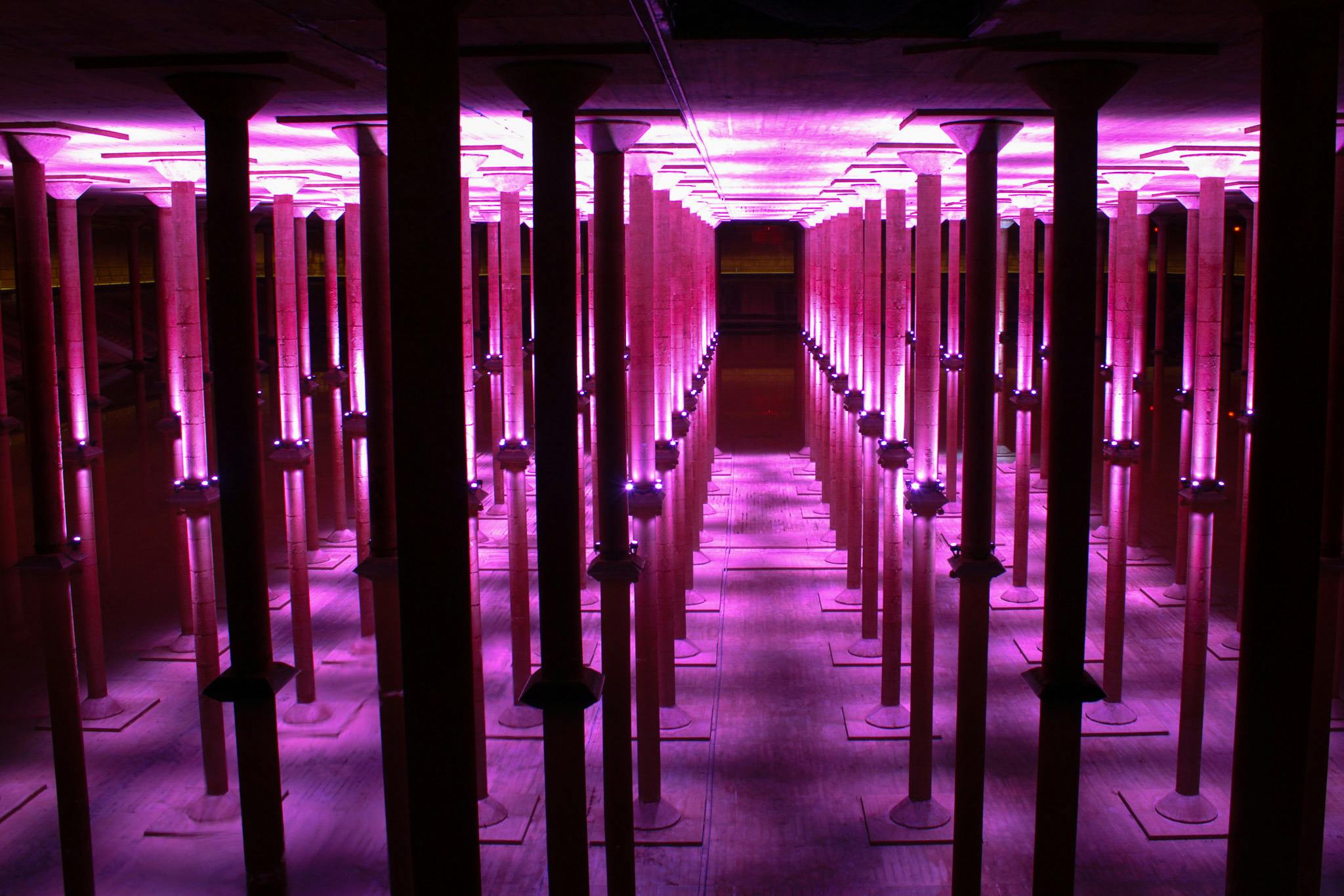 분홍빛이 비추는 기둥이 줄지어 있는 방으로 대칭적이고 미래지향적인 분위기를 연출합니다.