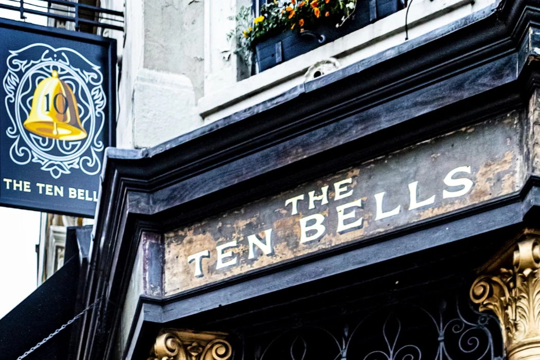 A sign reading 'The Ten Bells' above a doorway, with a flower box and ornate architectural details visible.