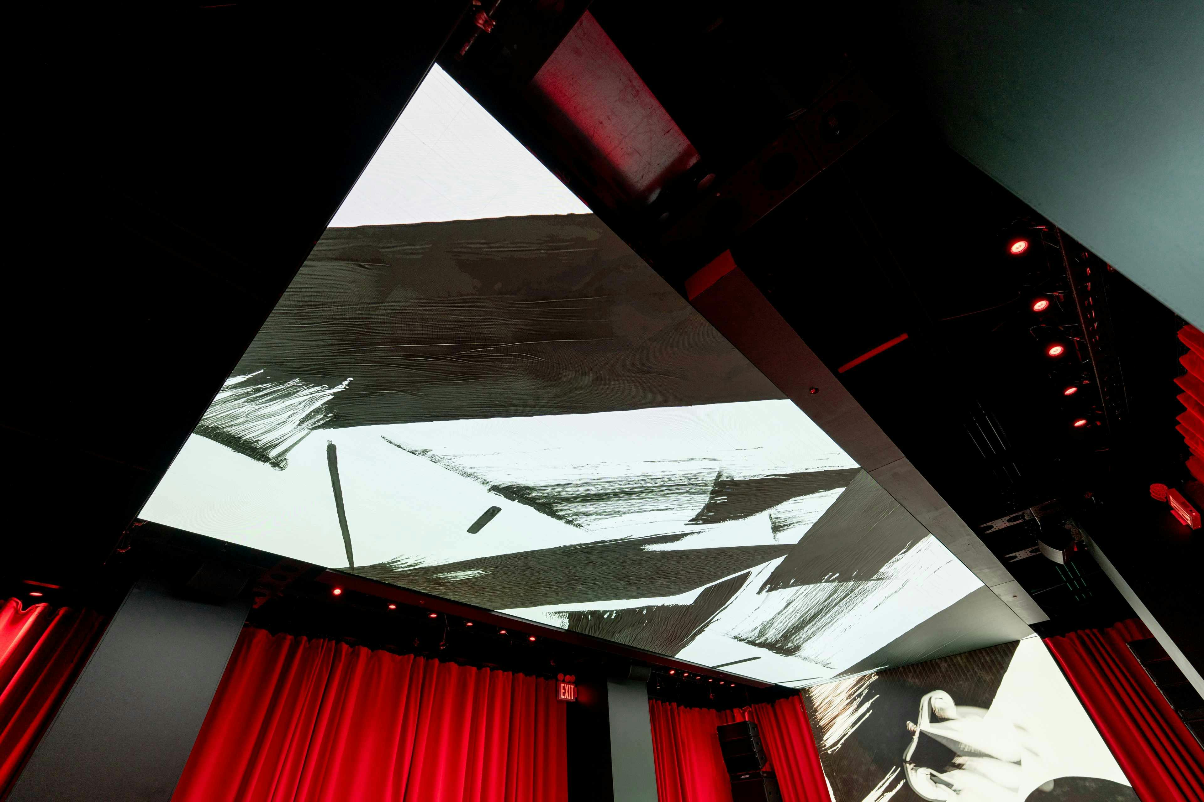 Ceiling with abstract black and white art, red curtains below, and dark fixtures.