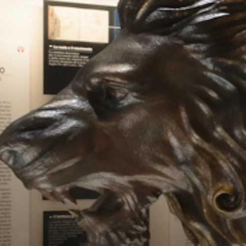 Museivisning med trämodeller av mekaniska uppfinningar, en stor lejonskulptur och informativa paneler på väggarna.