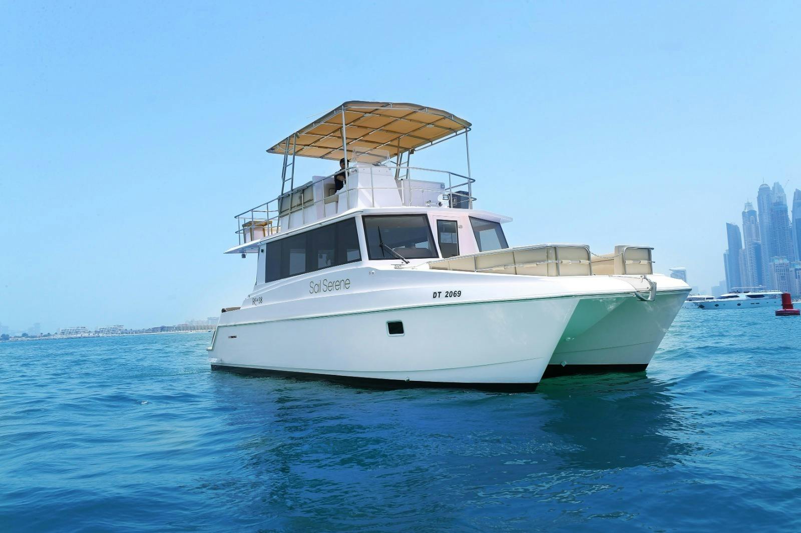 A white boat named "Sol Serene" with a canopy on top, floating on calm blue water under a clear blue sky.