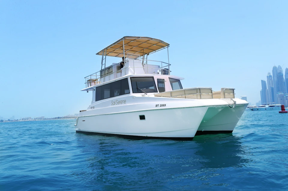 A white boat named "Sol Serene" with a canopy on top, floating on calm blue water under a clear blue sky.