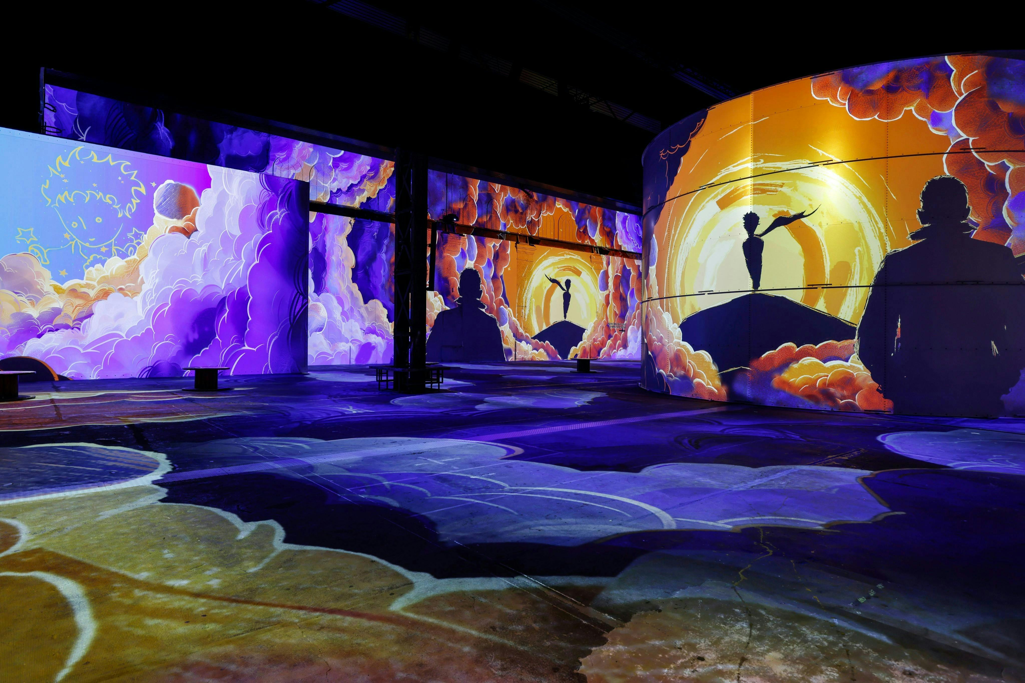 Εμβληματική ψηφιακή εγκατάσταση τέχνης με ζωντανές προβολές σιλουέτας και πολύχρωμα μοτίβα που μοιάζουν με σύννεφα στους τοίχους.