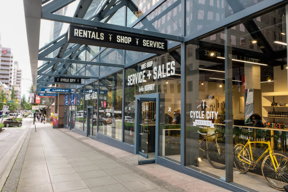 Storefront of Cycle City, a bike shop offering rentals, sales, and services. Large glass windows and doors, street view.