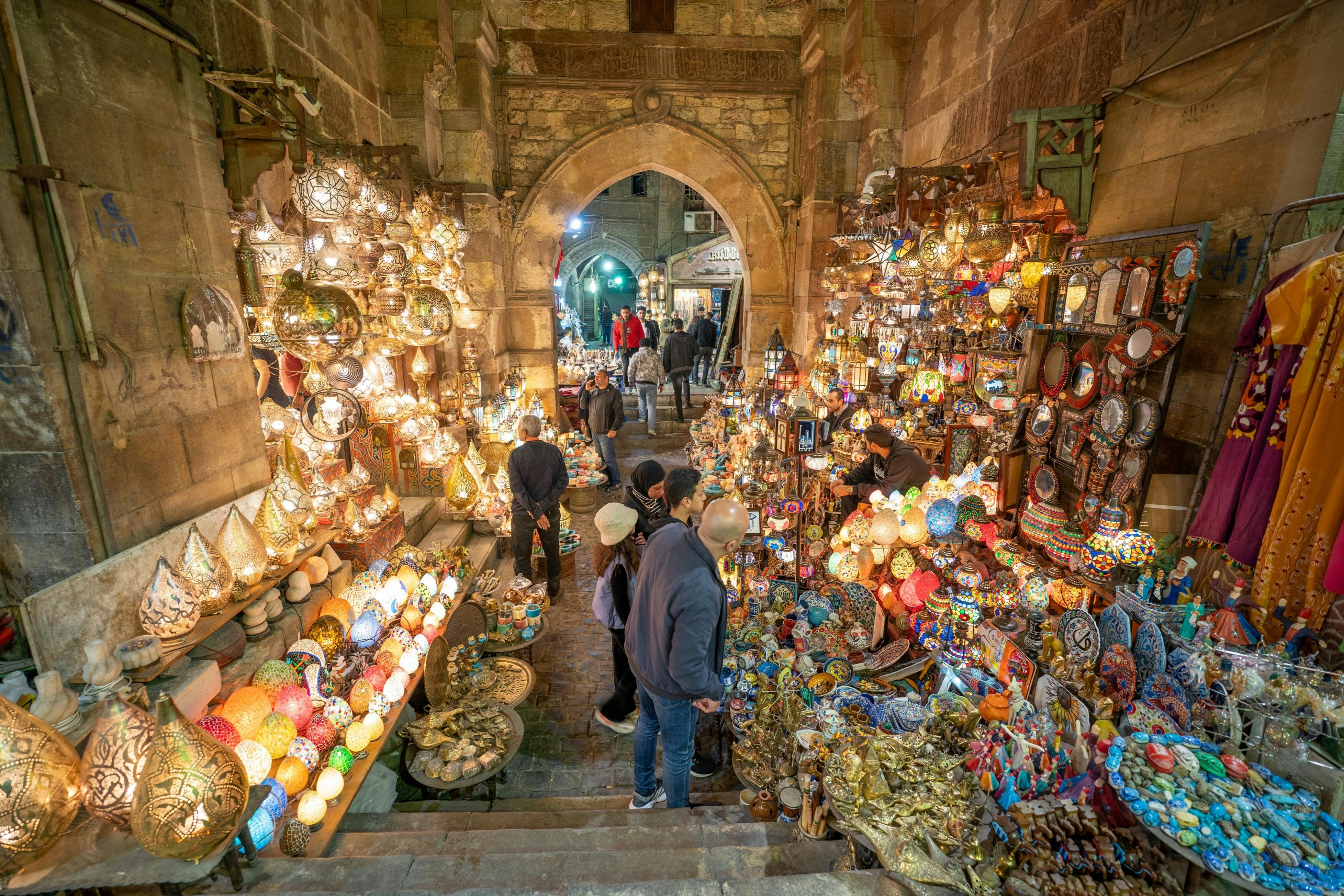 色とりどりのランプや装飾品が飾られ、人々が閲覧している賑やかな市場の屋台。 アーチウェイは、バックグラウンドでより多くの店舗につながります。