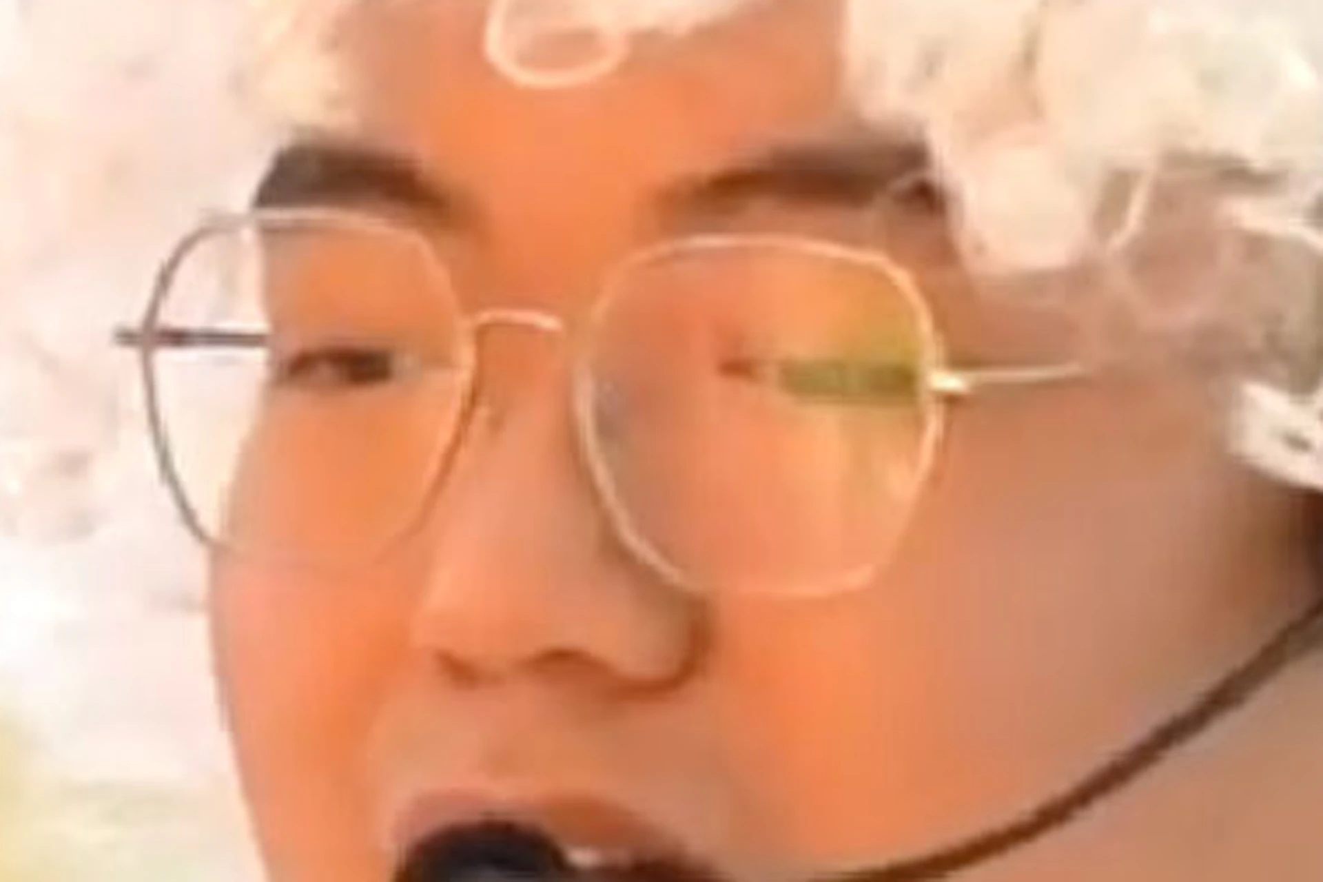 A person with a white wig, glasses, and a lab coat performing an experiment with flames on their gloved hands.