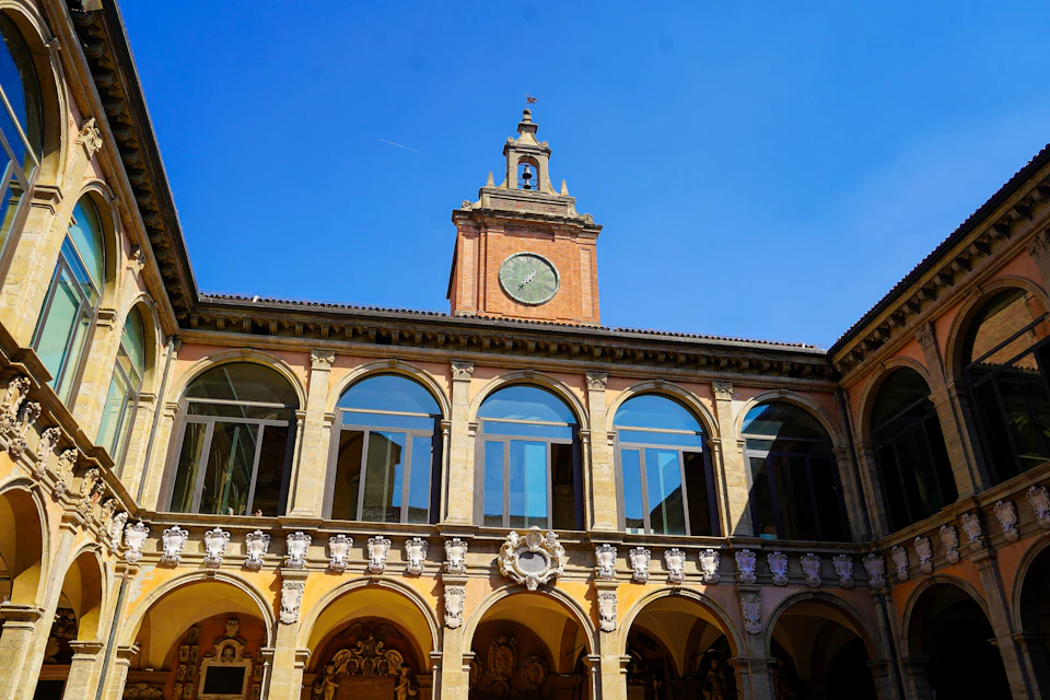 A historic building with arched windows, a clock tower, and intricate architectural details, under a clear blue sky.