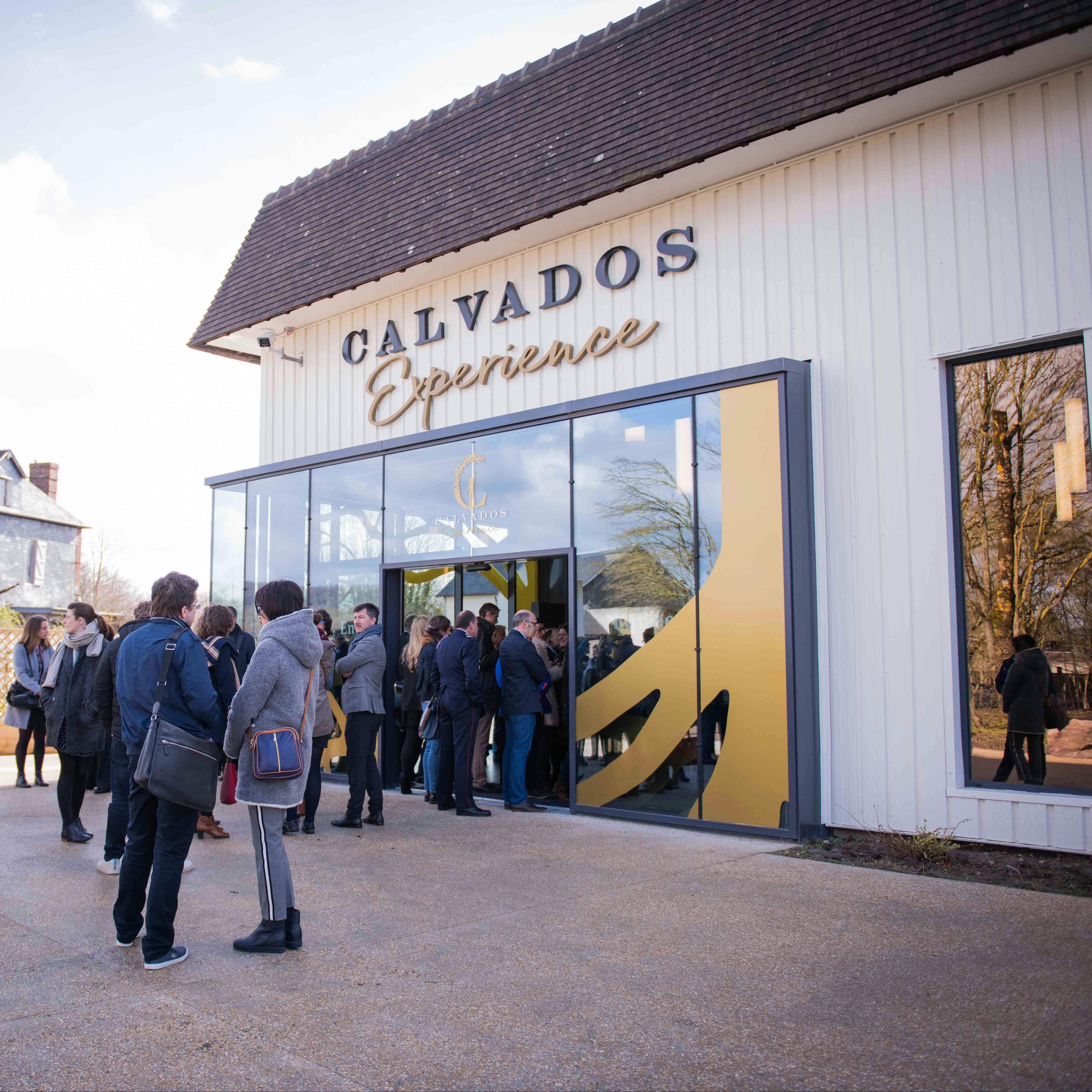 La gent es va reunir a l'entrada d'un edifici amb un cartell que deia "Calvados Experience" en lletres grans.