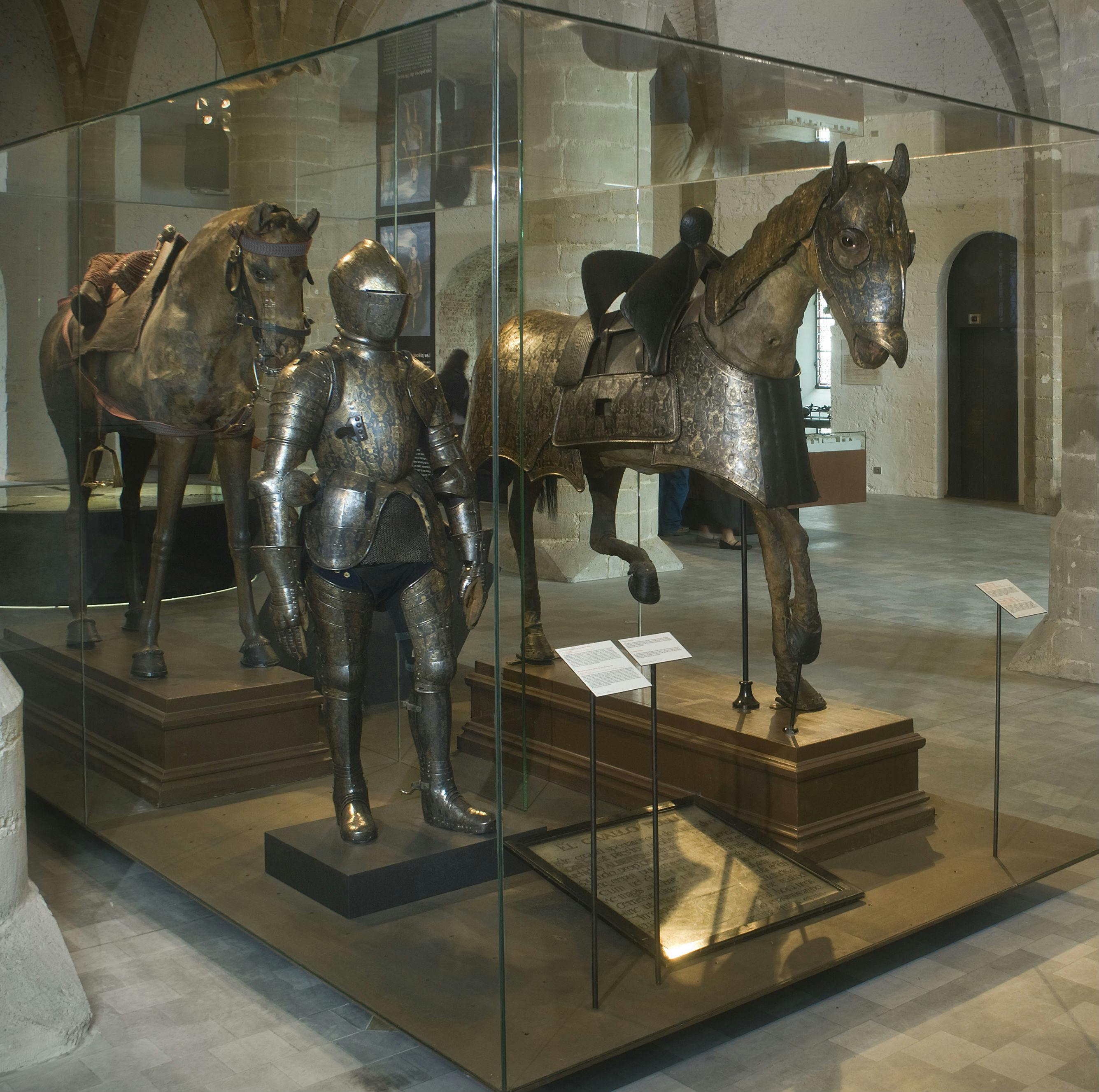 中世纪的骑士盔甲和两匹装甲马在历史博物馆的玻璃箱中陈列。