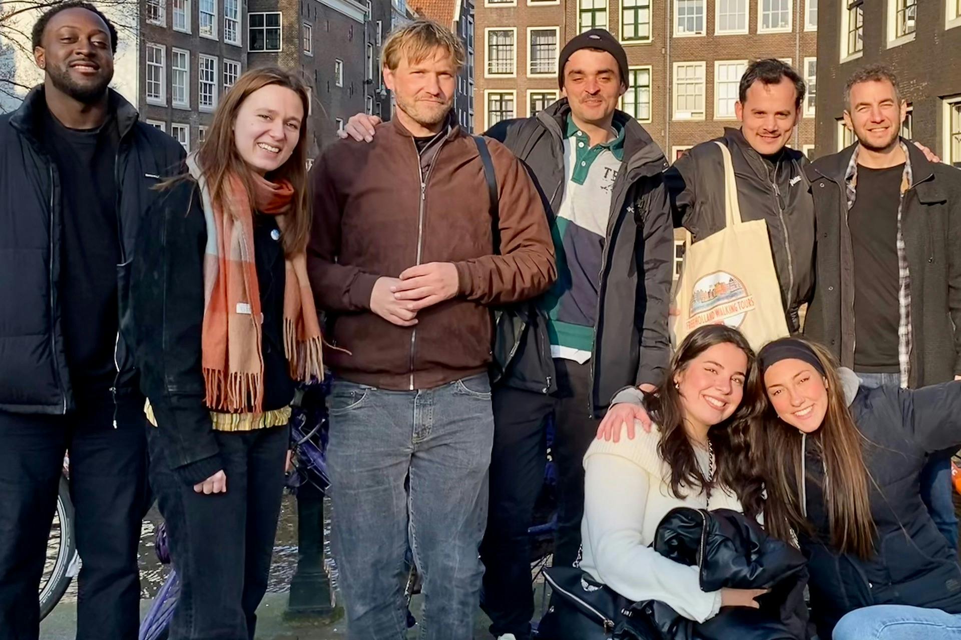 한 무리의 사람들이 낮에 건물 앞 야외에서 미소를 짓고 포즈를 취하고 있습니다.