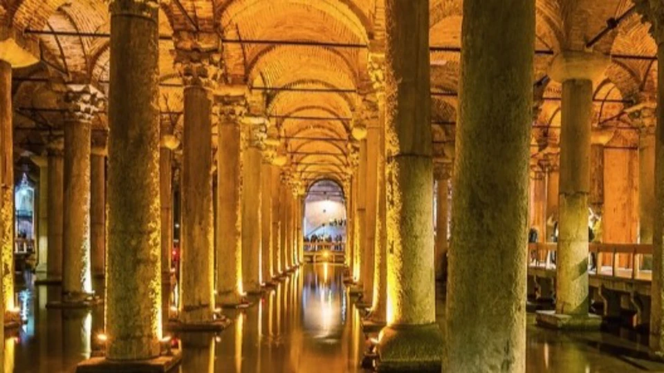 A grand underground cistern with tall illuminated columns, an arched ceiling, and water reflecting the lights.