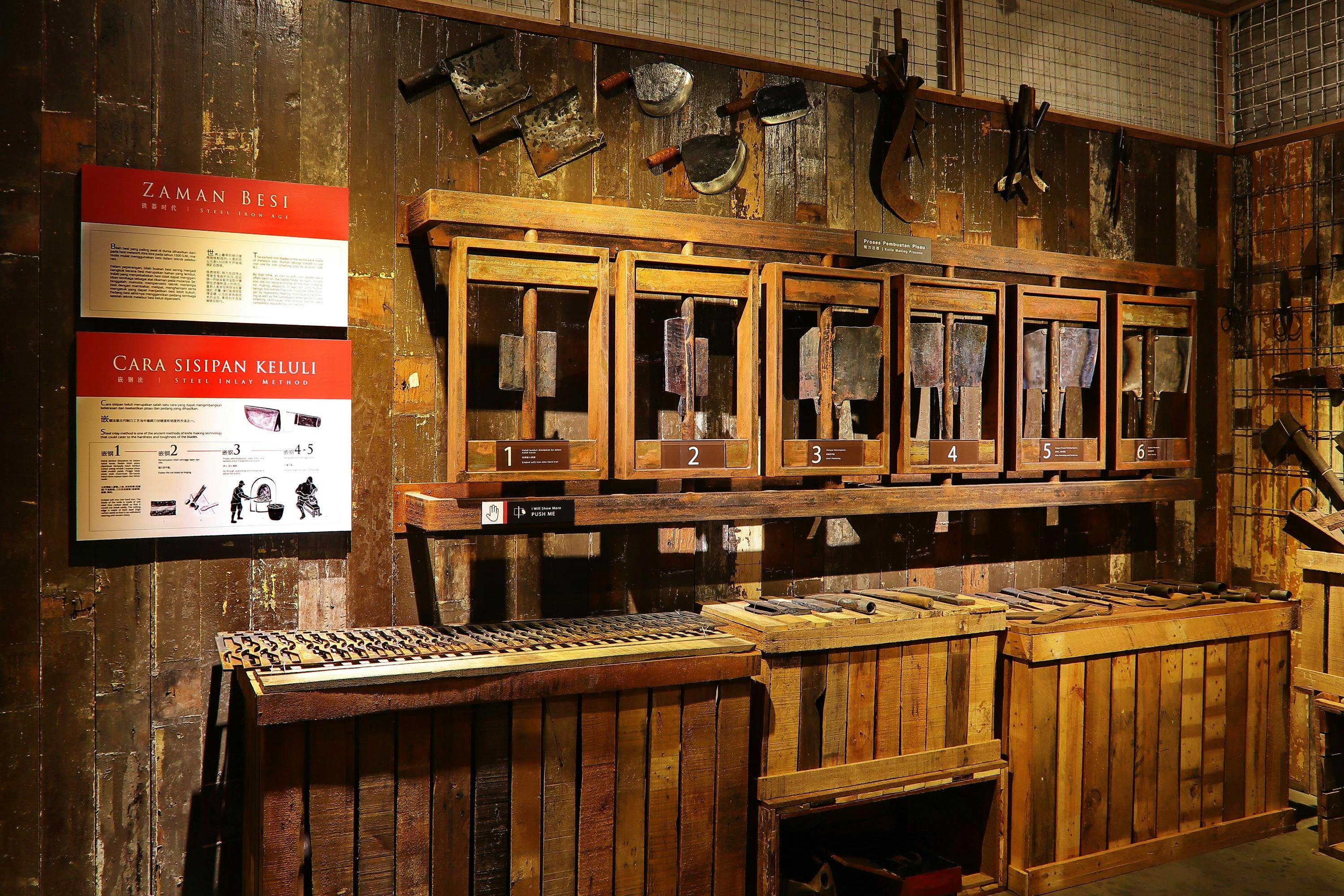 A wooden display of old tools and molds, labeled from 1 to 5, in a rustic setting with informational posters on the wall.