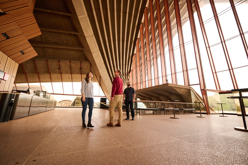 Travellers looking up in awe at the architecture and spherical solution of the Opera House shells